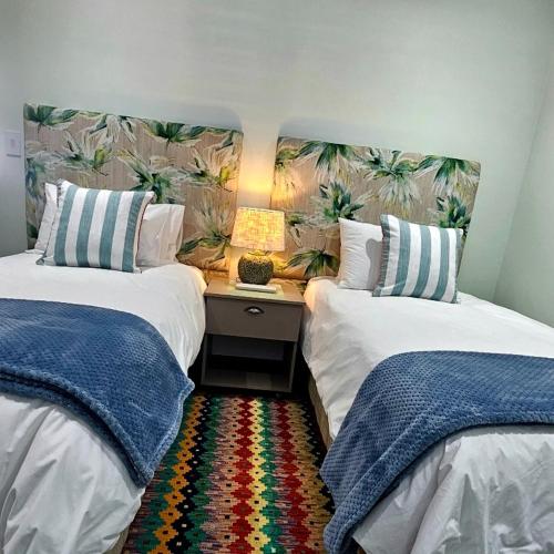 a bedroom with two beds and a desk with a lamp at Aandster in Paternoster
