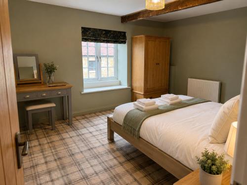 a bedroom with a bed and a desk and a mirror at The Ainsty in Thorp Arch