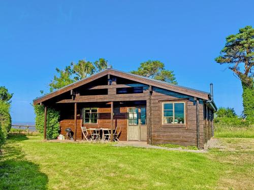 a small wooden cabin with a table in a field at Lapwing Lodge - Uk51640 in Carsethorn