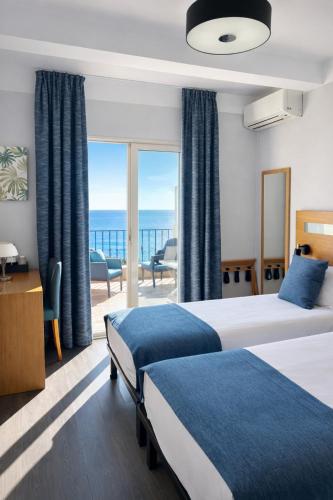 a hotel room with two beds and a view of the ocean at Hotel Miramar in Cap d'Ail