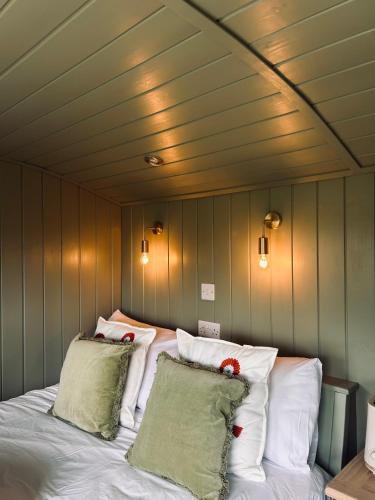 a bedroom with a bed with white pillows at Shepherds Hut in Shropshire with Swimming Pool in Shifnal