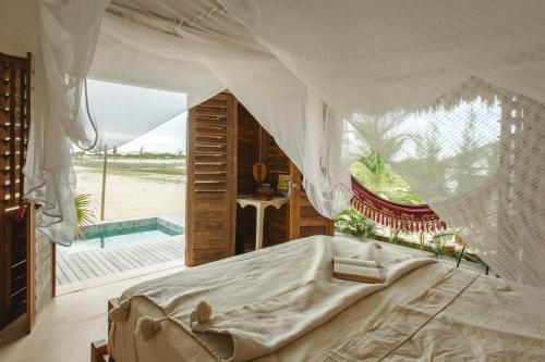 a bedroom with a bed with a canopy and a pool at Yvytu - Ohana Bungalow in Tatajuba
