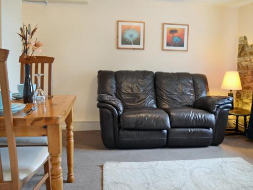 a black leather couch in a living room with a table at Bramling Apartment - Uk49302 in Woolfardisworthy