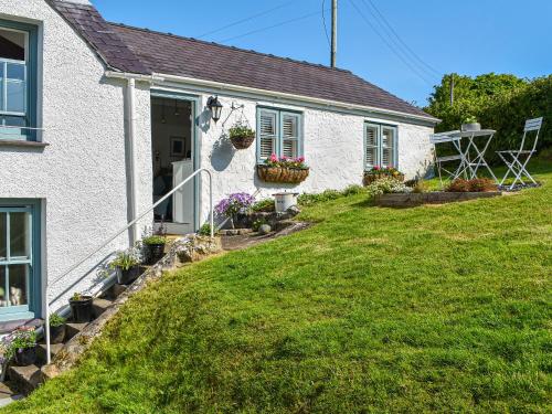 a white house with flowers in a yard at Tan Bryn - Uk44151 in Llanallgo