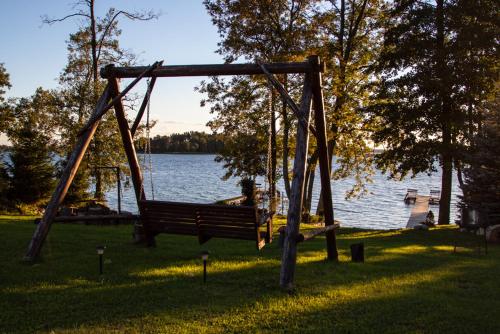 a wooden swing in a park next to a lake at Punkt Mazury in Sędki
