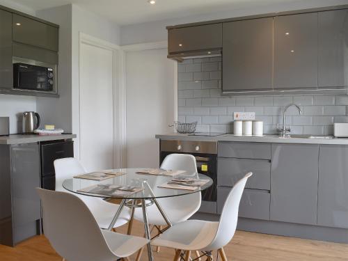 a kitchen with a glass table and white chairs at Sycamore Apartment - Uk49305 in Woolfardisworthy