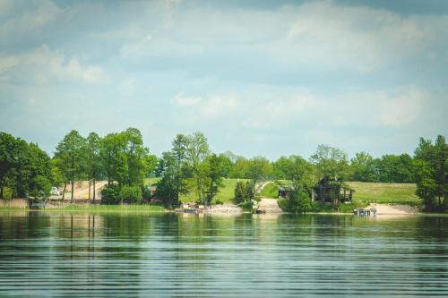 a view of a lake with a house in the distance at Punkt Mazury in Sędki