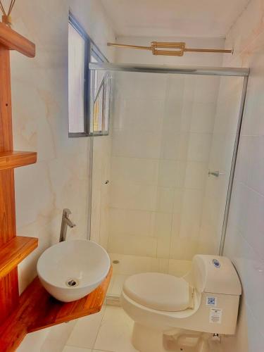 a white bathroom with a toilet and a sink at Casa Vacanza Apartamentos in Leticia