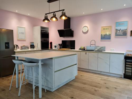 a kitchen with pink walls and a large island with stools at Au B'Honneur de Blois in Blois