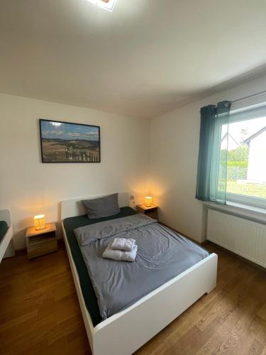 a bedroom with a bed with two lamps and a window at Ferienwohnung Adelsried 1 in Adelsried