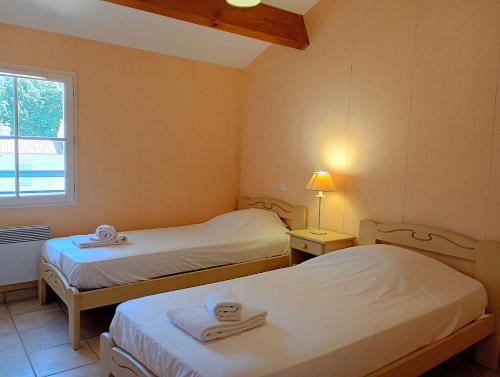two beds in a small room with a window at Villa l Albatros - Coex in Coëx