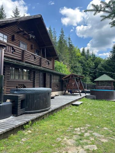 a wooden house with a playground in front of it at Володимирська садиба in Migovo