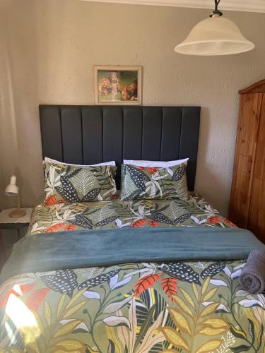 a bed with a black head board and pillows at Cave view Cottages in Muldersdrift