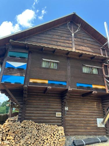 a wooden house with windows and a pile of wood at Володимирська садиба in Migovo