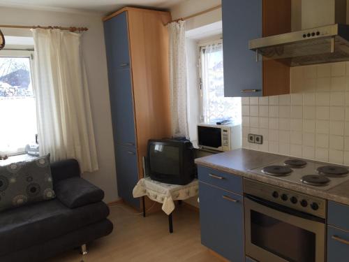 a kitchen with a stove and a couch and a tv at Haus Stainer in Lofer