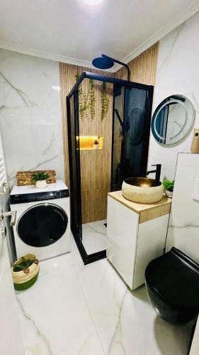 a bathroom with a shower and a washing machine at Escapist Apartments in Niš