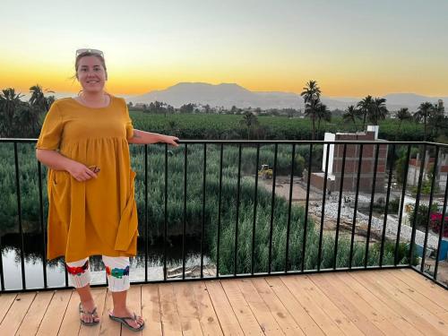 a woman standing on a balcony with the sunset in the background at Villa Mena Luxor in Luxor