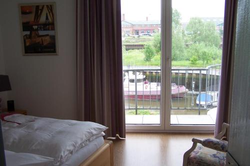Un dormitorio con una cama y un balcón con puerta corrediza de vidrio. en Marina 68/70, en Cuxhaven