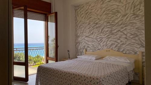 a bedroom with a bed and a balcony with the ocean at Park Hotel Gianfranco in Roccella Ionica