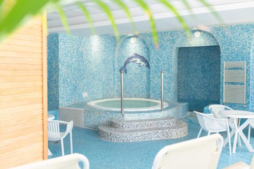 a tub in a blue room with white chairs at Kikelet Club Hotel in Miskolctapolca