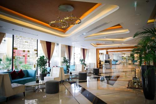 eine Lobby mit Stühlen und Tischen und einem Kronleuchter in der Unterkunft Century Hotel Doha in Doha