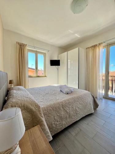 a white bedroom with a bed and a window at LaDependance Hotel Scilla in Scilla