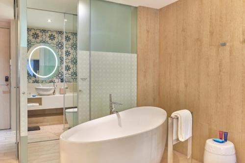 a bathroom with a white tub and a mirror at Village Hotel Katong by Far East Hospitality in Singapore