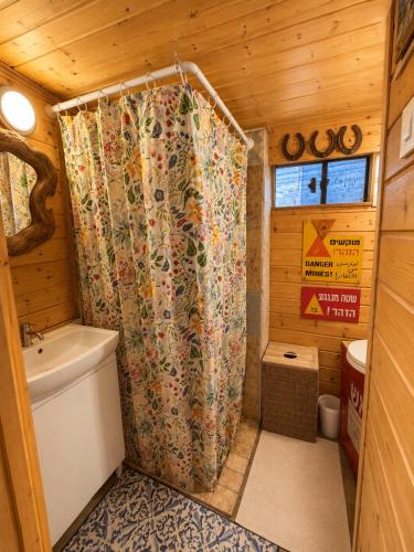 a bathroom with a shower curtain in a cabin at Green Bus in Beit Hillel