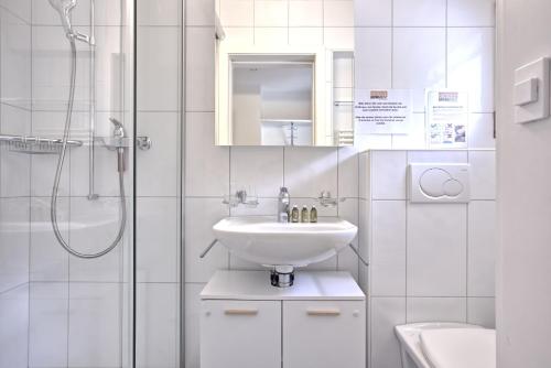 a white bathroom with a sink and a shower at Apartment Nussbaum - GRIWA RENT AG in Grindelwald