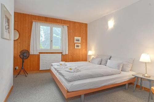a bedroom with a large bed and a window at Apartment Nussbaum - GRIWA RENT AG in Grindelwald