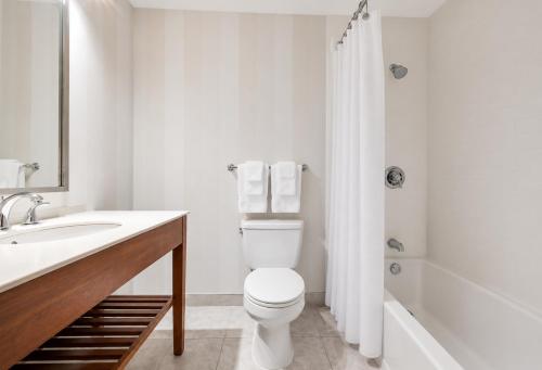 a white bathroom with a toilet and a sink at Quality Inn and Conference Centre in Pembroke