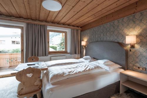 a bedroom with a large white bed and a window at Haus Wildschütz by Hotel Tirolerhof in Tux