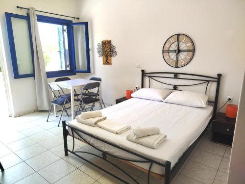 a bedroom with a bed and a table and a clock at Sarantakis Apartments in Agios Andreas