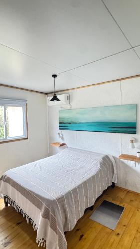 a white bedroom with a bed and a window at Brisa del Sur Lofts in La Paloma