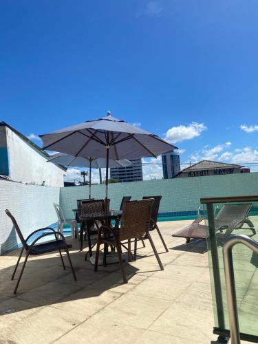 a table and chairs with an umbrella on a patio at Apto com localização privilegiada e piscina - Charmoso e completo in Recife