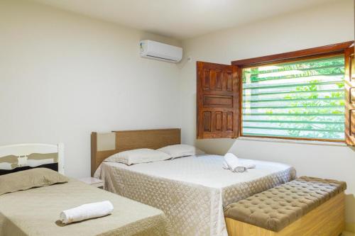 a bedroom with two beds and a window at Recanto do mar in Ilhéus