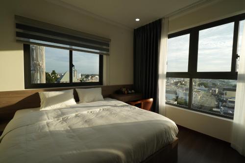 a bedroom with a large bed and two large windows at Olivia Hotel in Ấp Thành