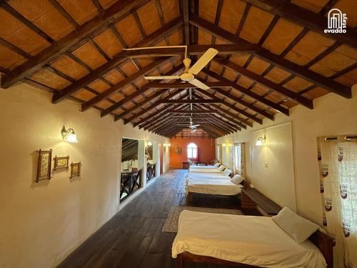a row of beds in a room with wooden ceilings at The Thota Mane by evaddo stays in Sakleshpur