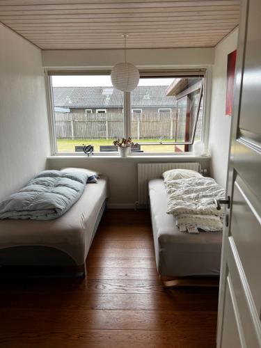 two beds in a small room with a window at Dejlig og hyggelig hus i Thyborøn in Thyborøn
