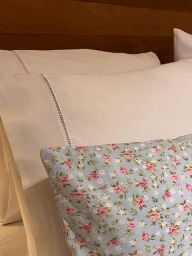 a bed with a pillow with a floral blanket on it at Jardim Secreto - Itaipava in Itaipava