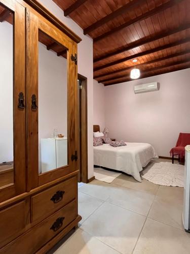 a bedroom with a bed and a dresser at Jardim Secreto - Itaipava in Itaipava