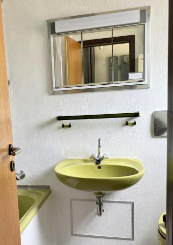 a bathroom with a yellow sink and a mirror at Ferienhaus Hasenglück in Waldbrunn