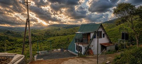 a small house with a green roof on a hill at Kalathil Guest House in Vagamon
