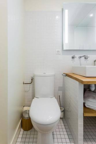 a white bathroom with a toilet and a sink at Appartement quartier St Michel climatisé près des quais avec parking in Bordeaux