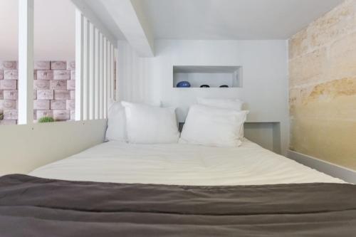 a bedroom with a bed with white sheets and pillows at Appartement quartier St Michel climatisé près des quais avec parking in Bordeaux