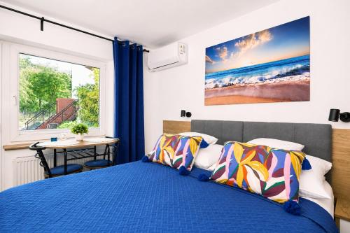 a bedroom with a blue bed and a window at Baltic Sand - Apartamenty I Pokoje Władysławowo in Władysławowo