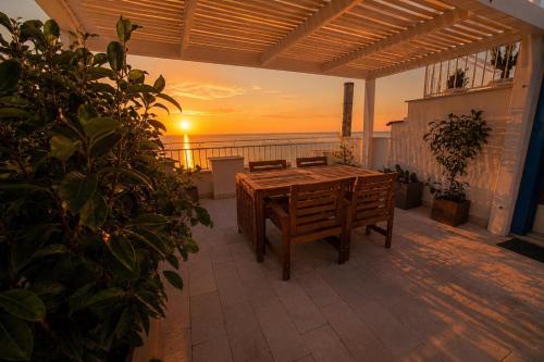 a table and chairs on a balcony with the sunset at Vico Lungo 9, Peschici in Peschici