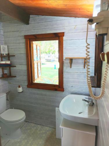 a bathroom with a toilet and a sink and a window at CAMPING A GRANDELLA in El Franco