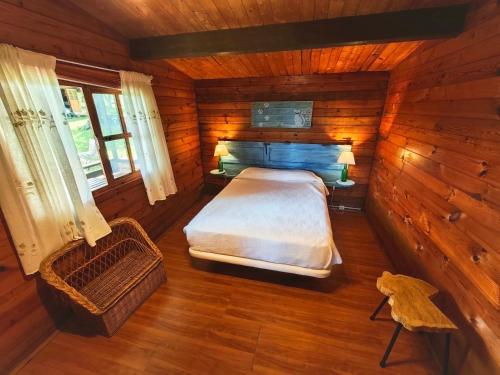 a bedroom in a log cabin with a bed and a chair at CAMPING A GRANDELLA in El Franco