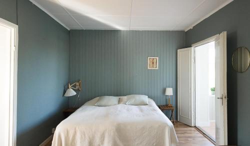 a bedroom with a bed and a blue wall at Spjutstorp's old school and rectory 2 in Tomelilla
